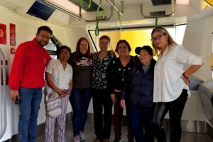 Fotografia grupal de la comunidad de cable y buses en la Escuela Vagon del Metro junto a Carolina Martinez, Gerente de La Rolita