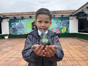 Fotografia de niño de la comunidad del TransMiCable con matera reciclada