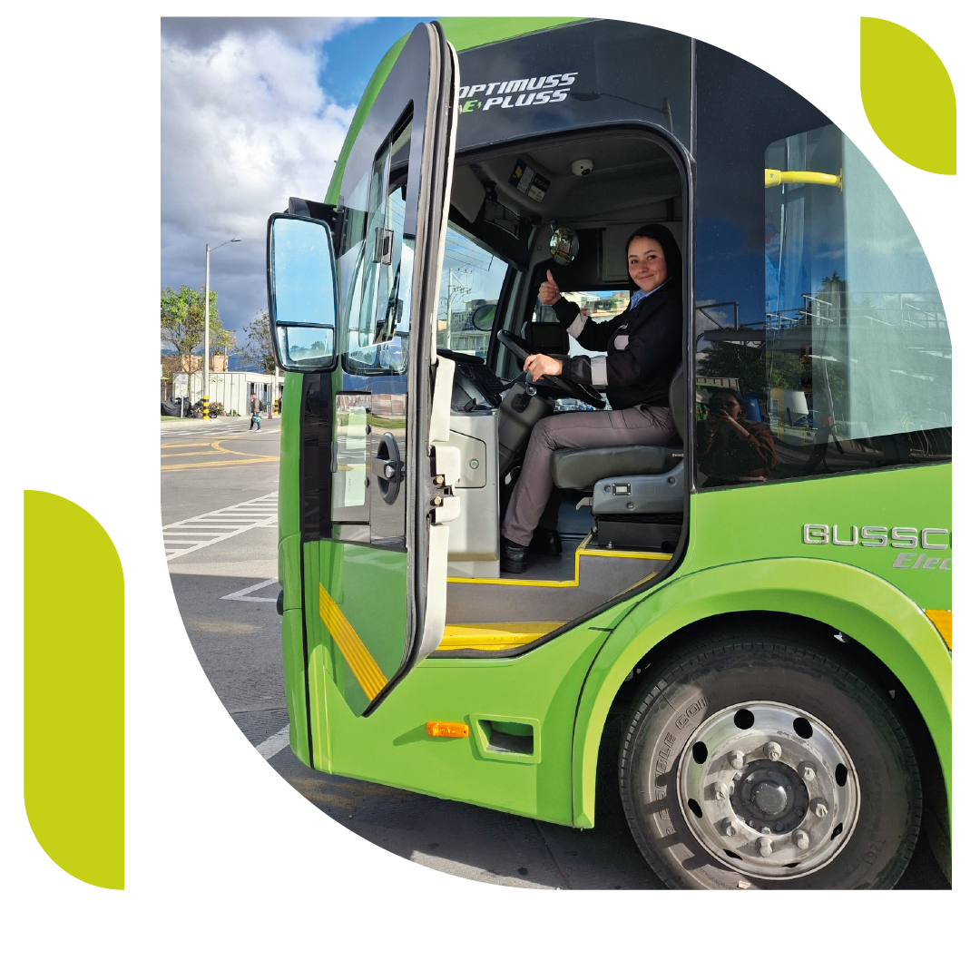 Operadora sentada en la silla del conductor de un bus eléctrico La Rolita. Sonriendo y levantando el pulgar de la mano izquierda.