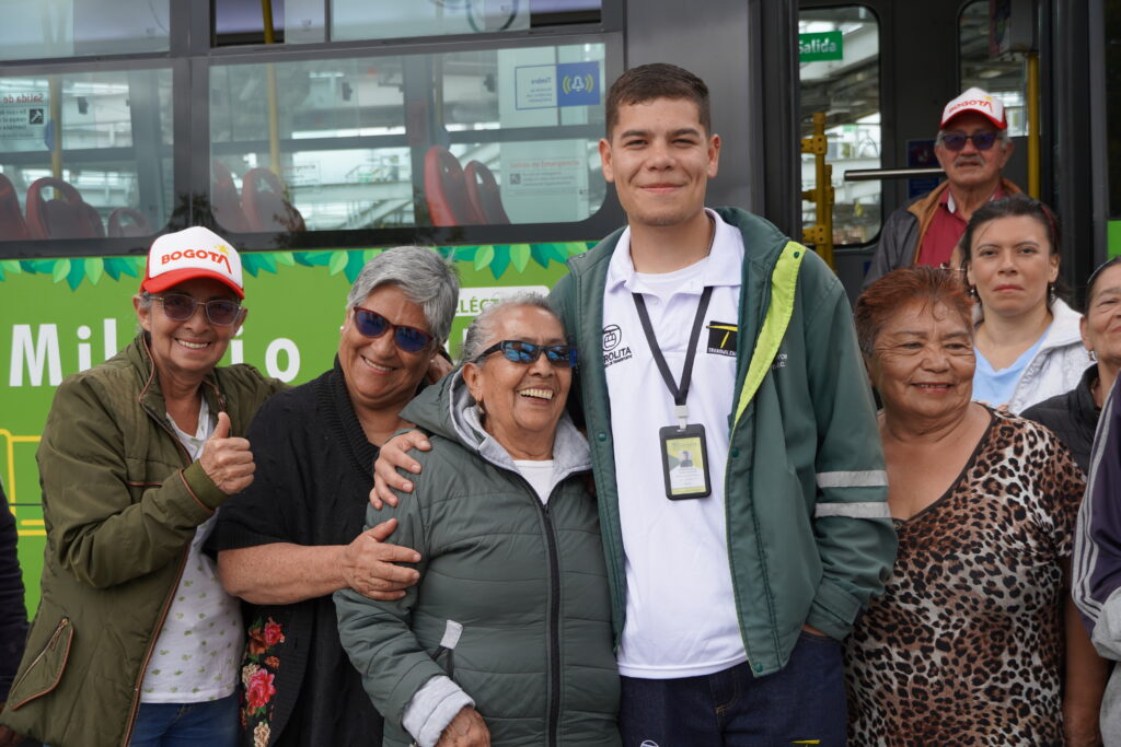 Grupo de personas mayores al lado de un guía social, con el bus de fondo.