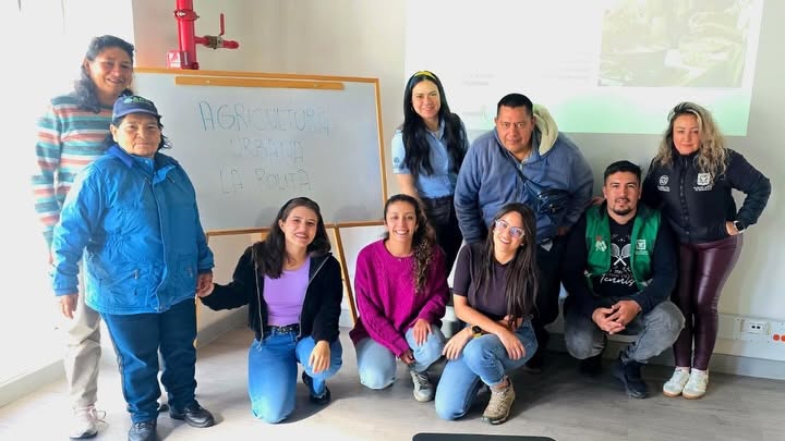 Equipo de 9 personas en un salón con la imagen de fondo del Curso de Agricultura Urbana.
